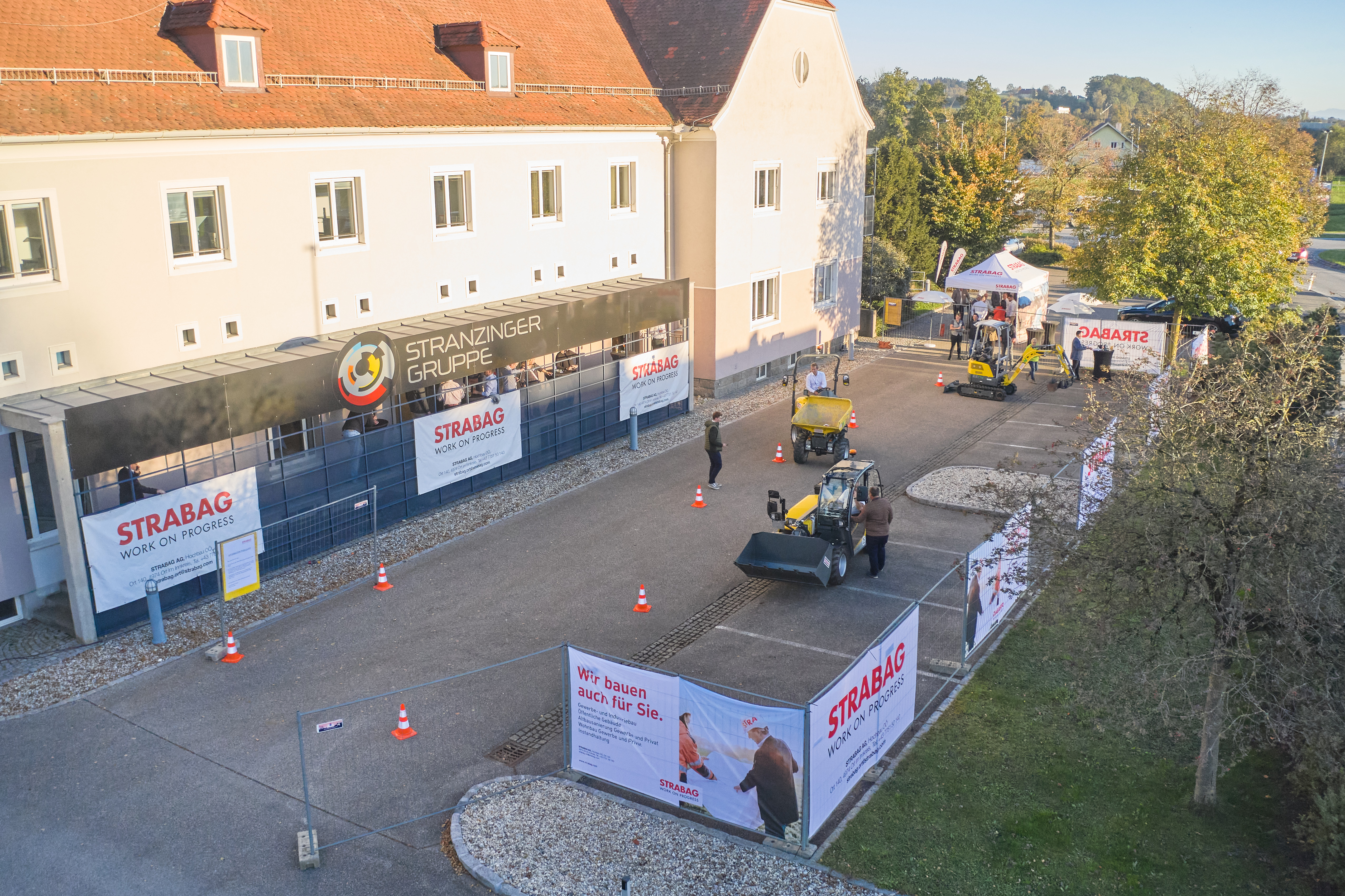 Foto von eines Gebäudes mit einem Parkplatz umgeben von Bauzäunen