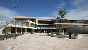 Foto von einem modernen Gebäude bei blauem Himmel, davor ein gepflasterter Platz