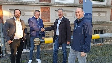 Foto vom vier Männer die lächelnd in die Kamera schauen. 