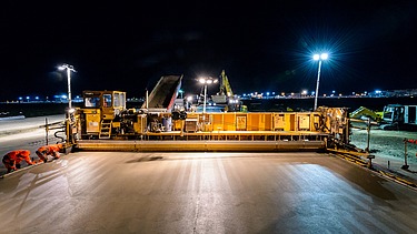 Foto einer gelben Betonbaumaschine bei Nacht bei Flutlicht
