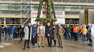 Foto von mehreren Personen vor dem Richtkranz von der Baustelle des Gymnasiums in Köln Deutz. 