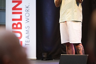 Foto von zwei Personen auf der Bühne. Sie spricht in ein Mikrophon.  