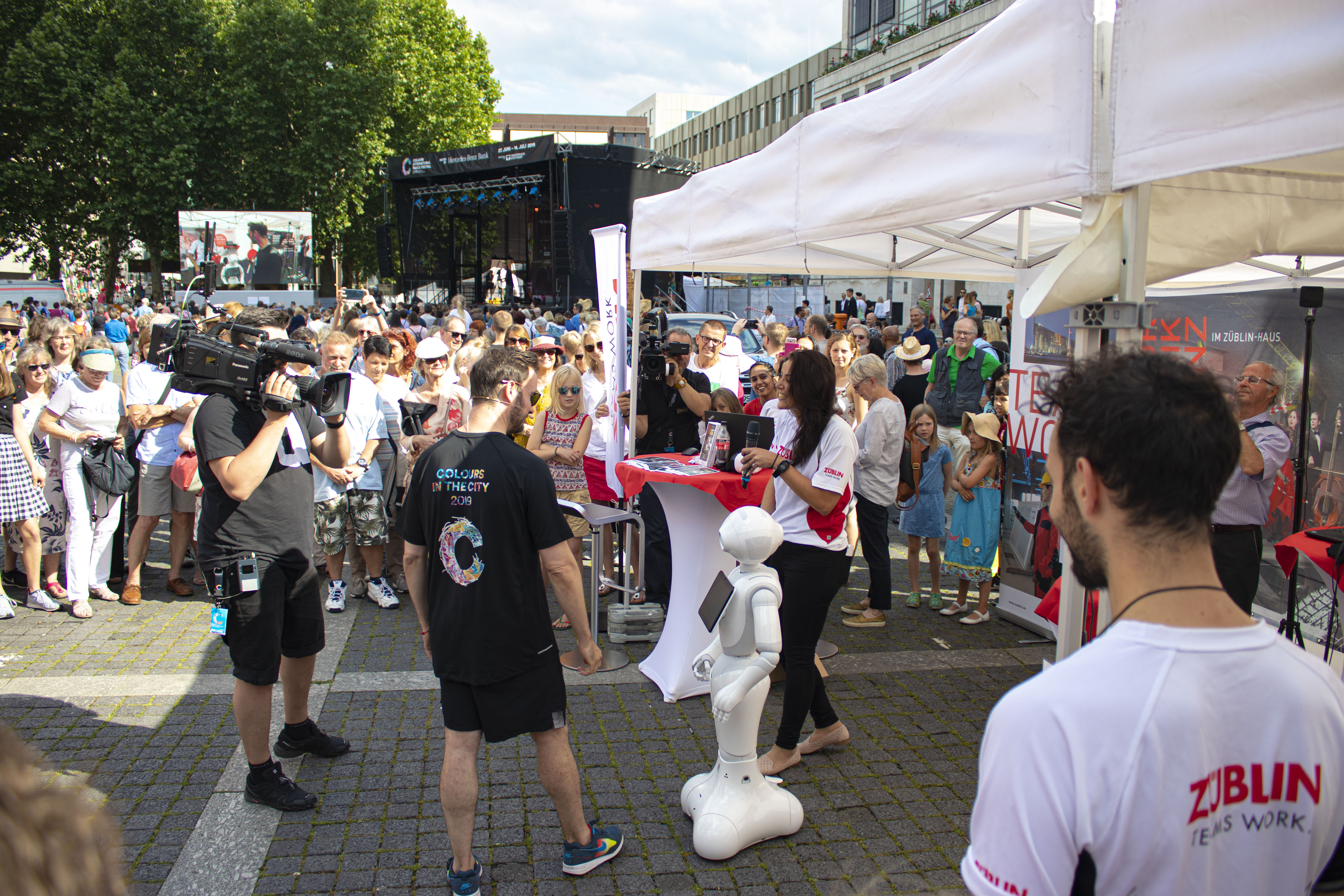 Foto von einem ZÜBLIN-Stand, wo ein Roboter gefilmt wird. Drumherum sind viele Personen versammelt    