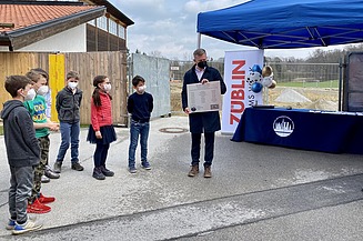 Foto von Kindern und einem Mann, die an einer Zeitkapsel-Zeremonie teilnehmen. 