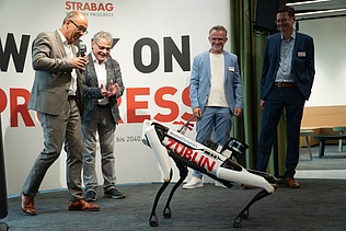 Foto von mehreren Personen, die einen Roboterhund in Aktion zuschauen. 