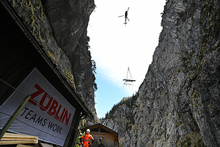 Foto von Hubschrauber, der Material in eine Schlucht abseilt.                 