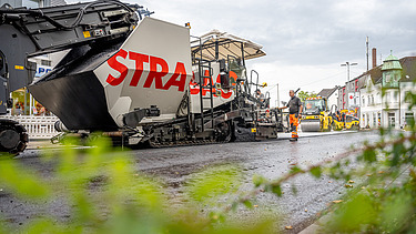 Foto einer großen Asphaltbaumaschine mit dem Schriftzug STRABAG auf der Seite