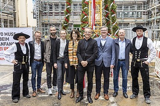 Foto von mehreren schick gekleideten Personen auf einer Baustelle.  