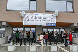 Foto vom Eingang des Berufsbildungswerk München.  Es vorm Eingang. Es herrscht eine ausgelassene Stimmung. 