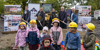 Foto vom symbolischen Spartenstich. Im Hintergrund sind mehrere Personen im Anzug zusehen. Im Vordergrund stehen Kinder, die einen Helm anhaben. 