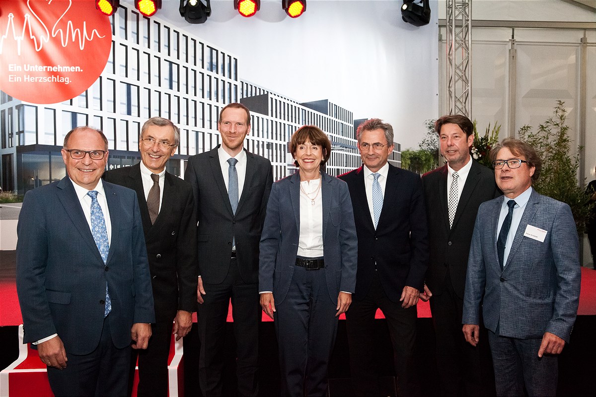 Foto von sieben Personen, die vor einem Plakat stehen