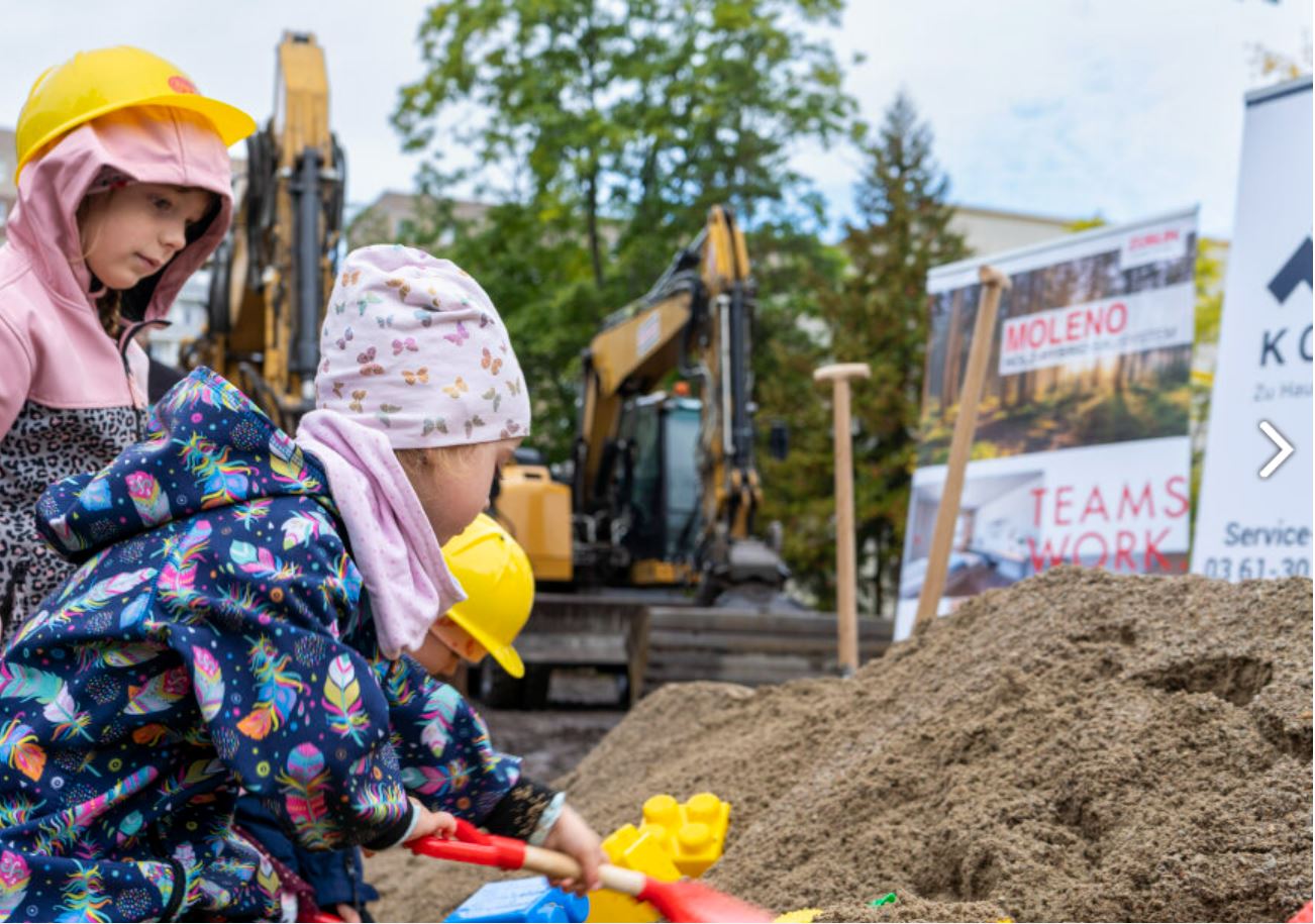 Foto von Kindern die eine Schaufel in die Erde stecken. 