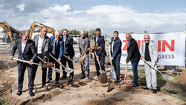 Das Bild zeigt Personen beim Spatenstich mit Schaufeln.