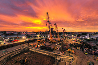 Baustelle mit Kränen bei Sonnenuntergang