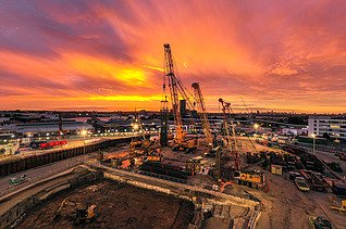 Baustelle mit Kränen bei Sonnenuntergang