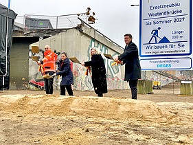 vier Personen schaufeln Sand