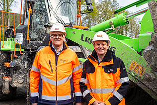 Two men in work clothes standing in front of a wheel loader