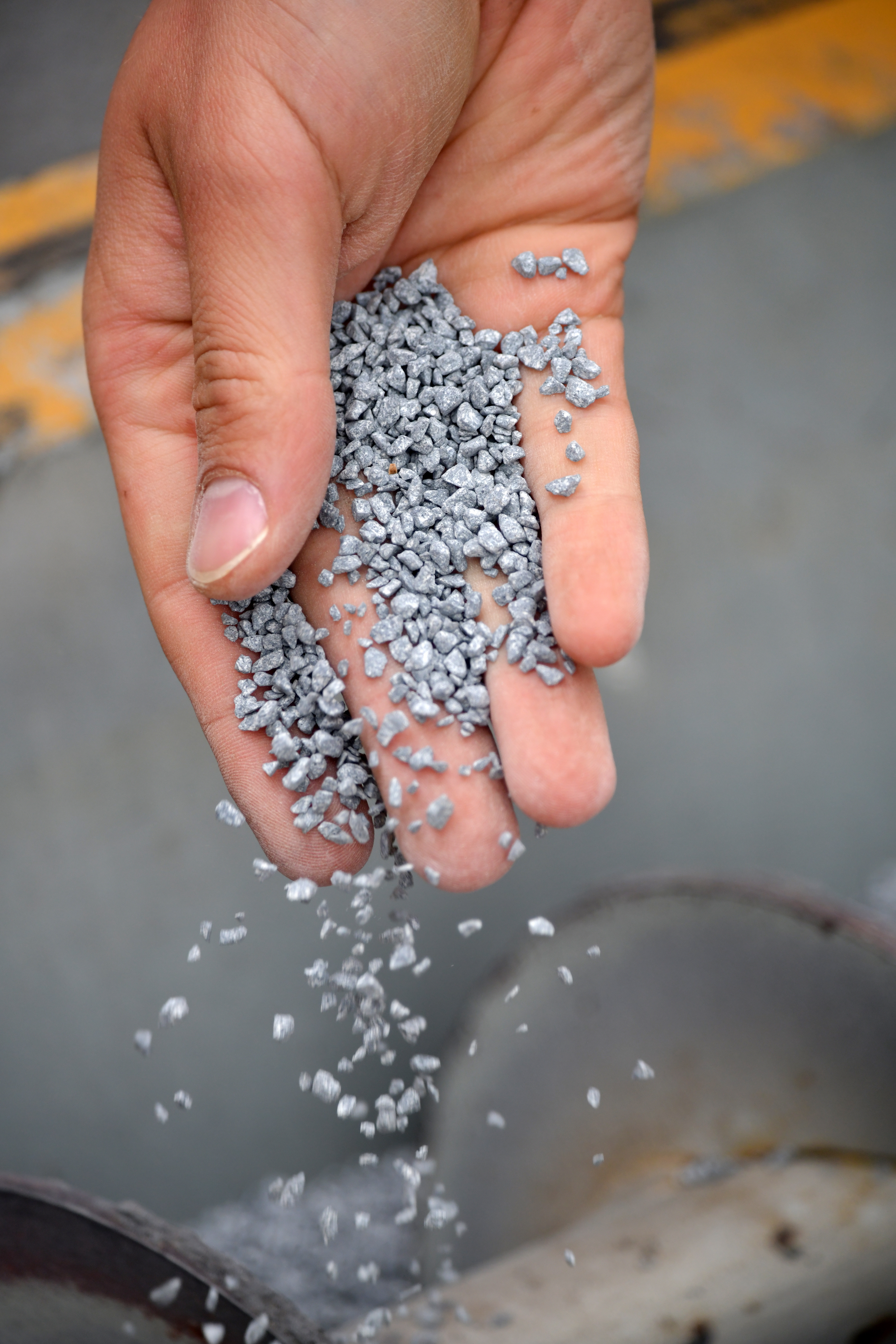 Foto einer Hand, die graue Kügelchen runter rieseln lässt