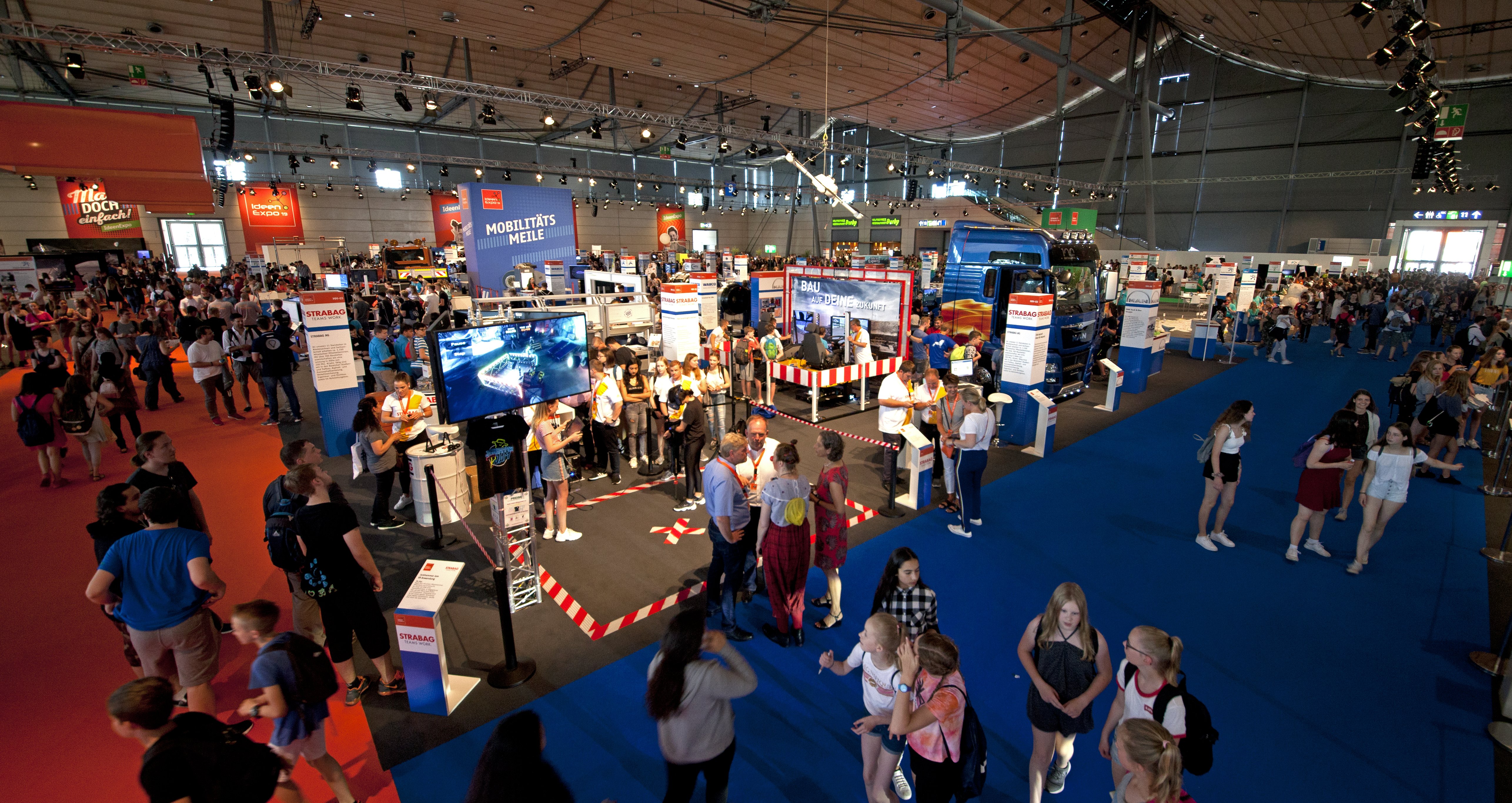 Foto einer Messehalle von innen mit vielen Personen an Messeständen