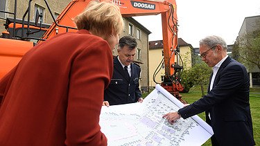 Foto drei Personen die sich Zeichnung anschauen. 