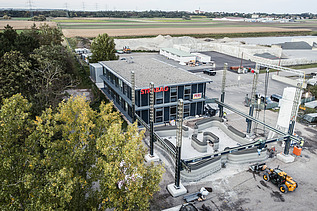 Aerial view of an office building with parking lot, some trees on the right