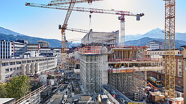 Foto von einer Baustelle eines Hochhaus umzingelt von mehreren Kränen