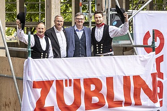 Foto von vier schick gekleideten Männern auf einem Gerüst. 