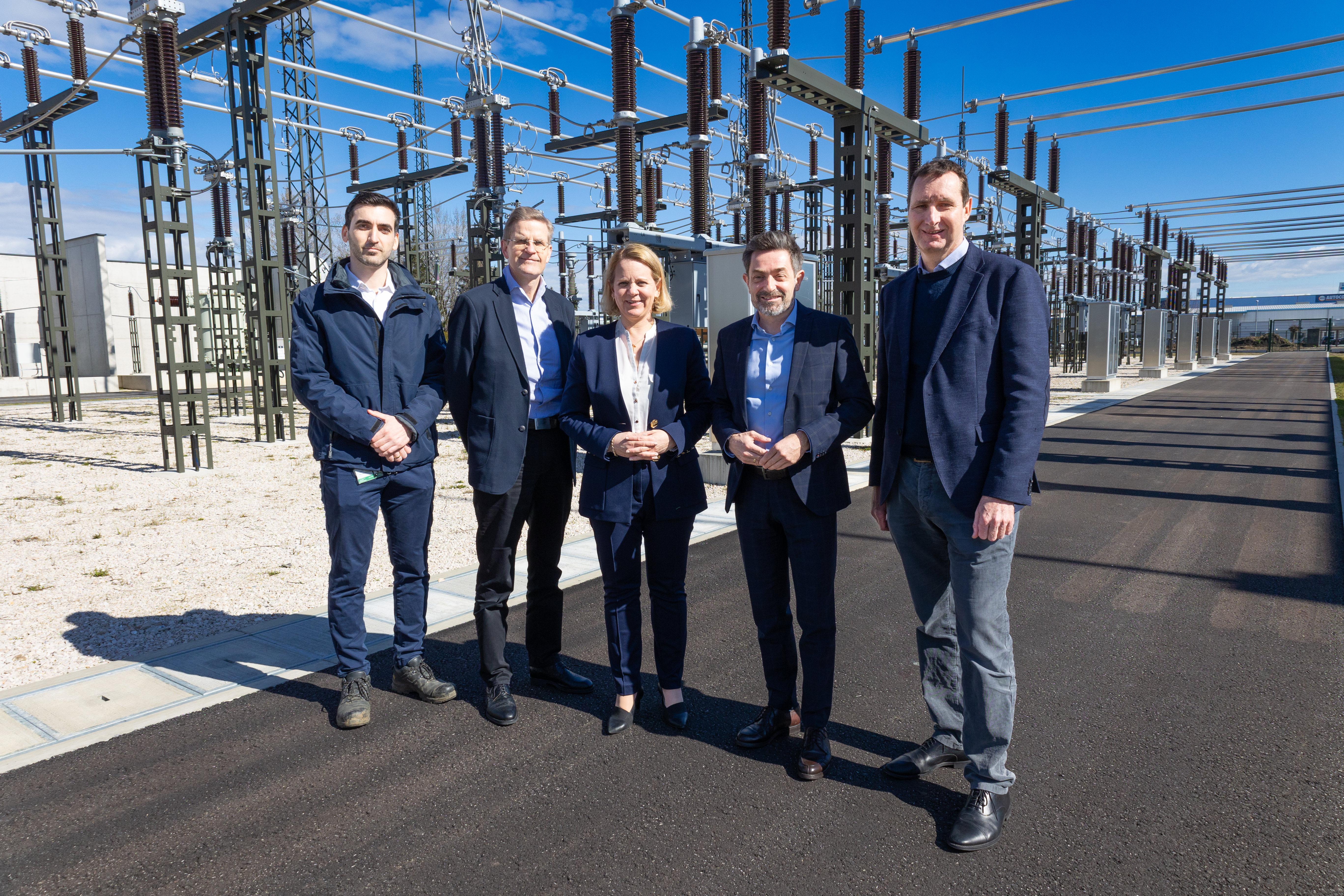 Foto von fünf Personen, die vor einem Umspannwerk stehen