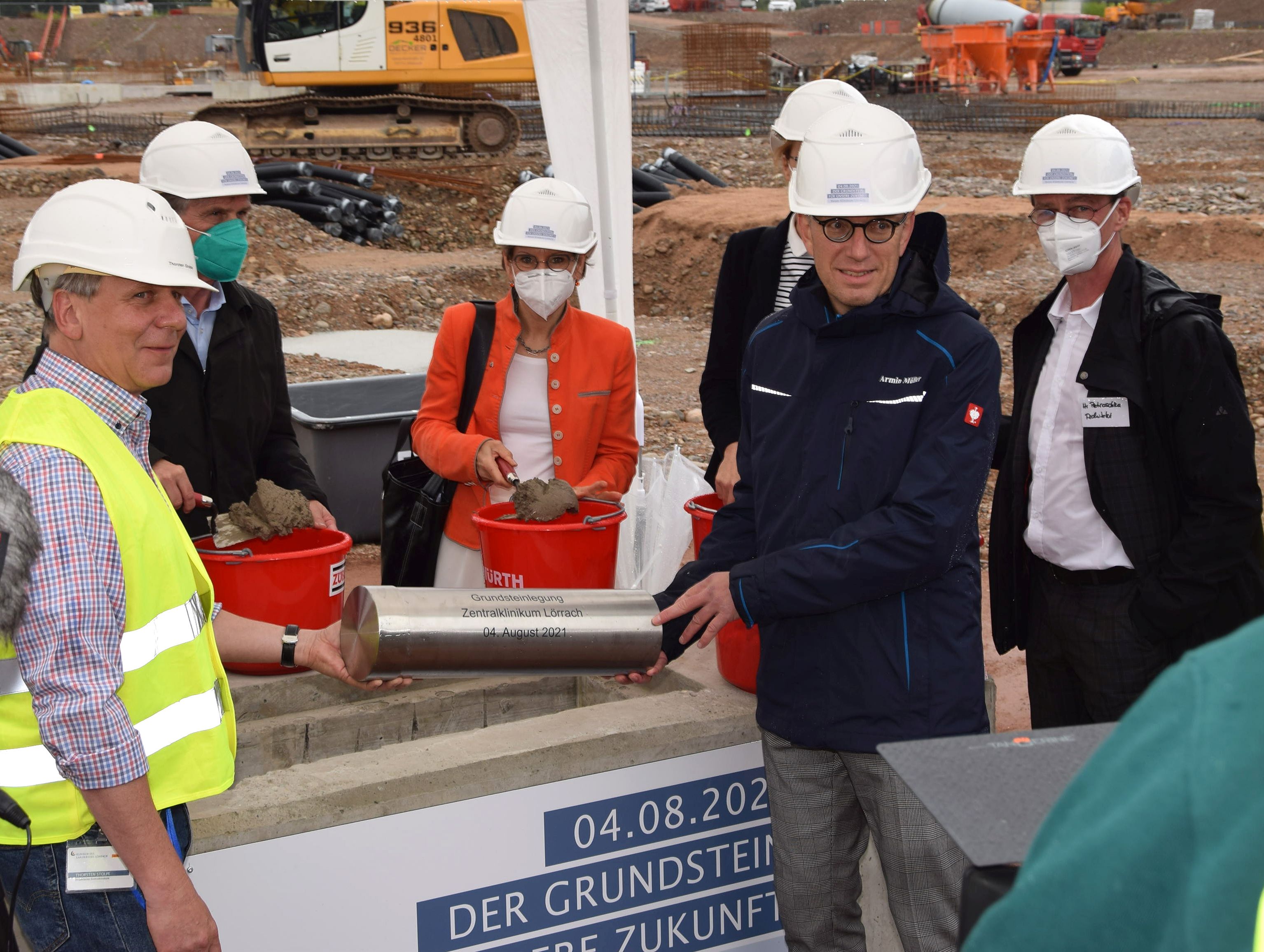 Foto von der Grundsteinlegung im Klinikum, mehrere Personen halten eine Zeitkapsel. 