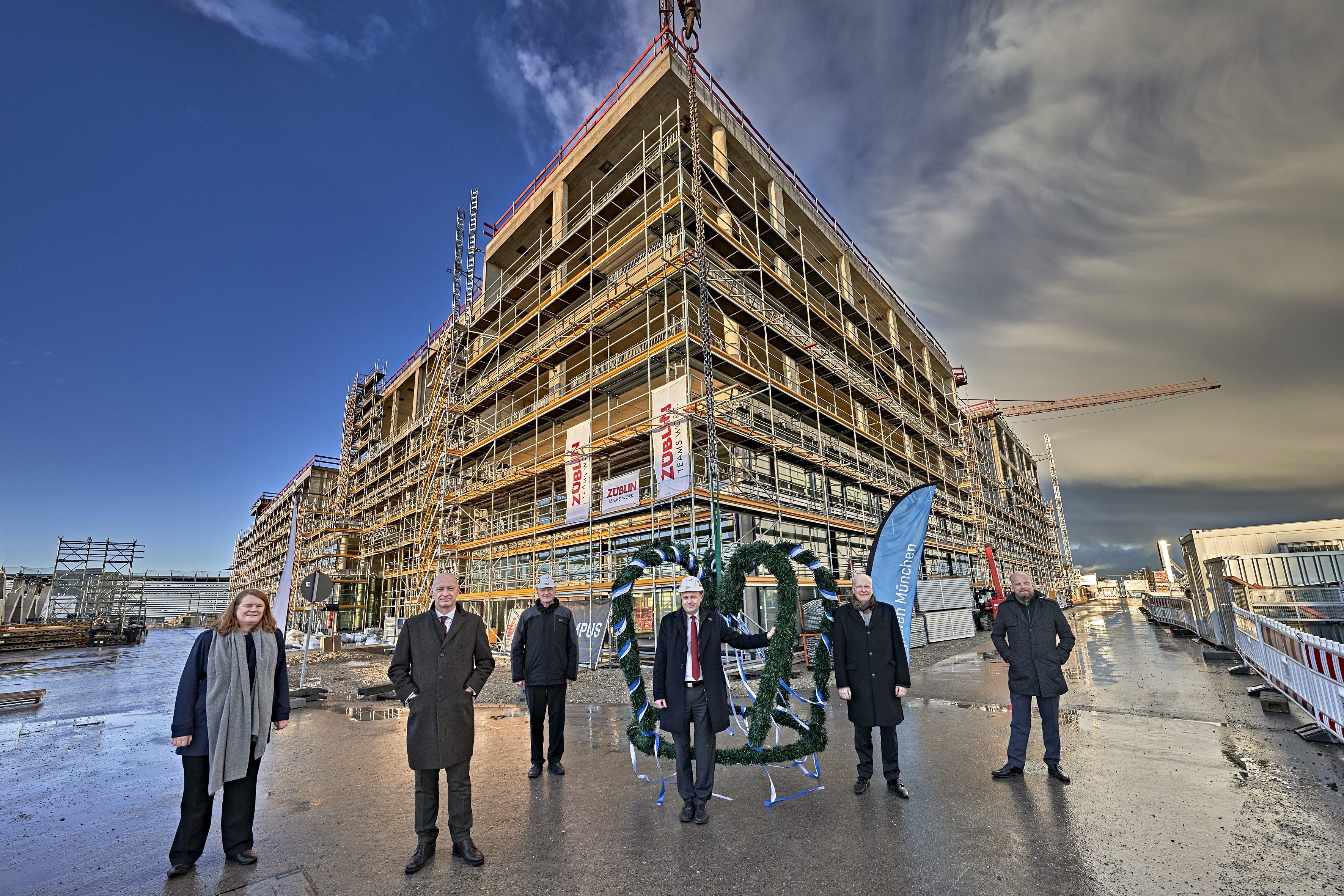 Foto von mehreren Personen die vorm Richtkranz stehen über dem LabCampus am Flughafen München.