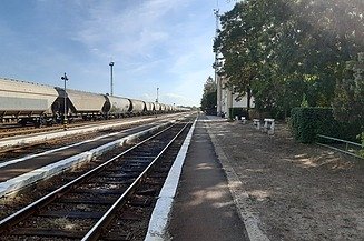 Foto von Bahngleisen bei blauen Himmel, auf einem Gleis steht ein Güterzug mit Waggons