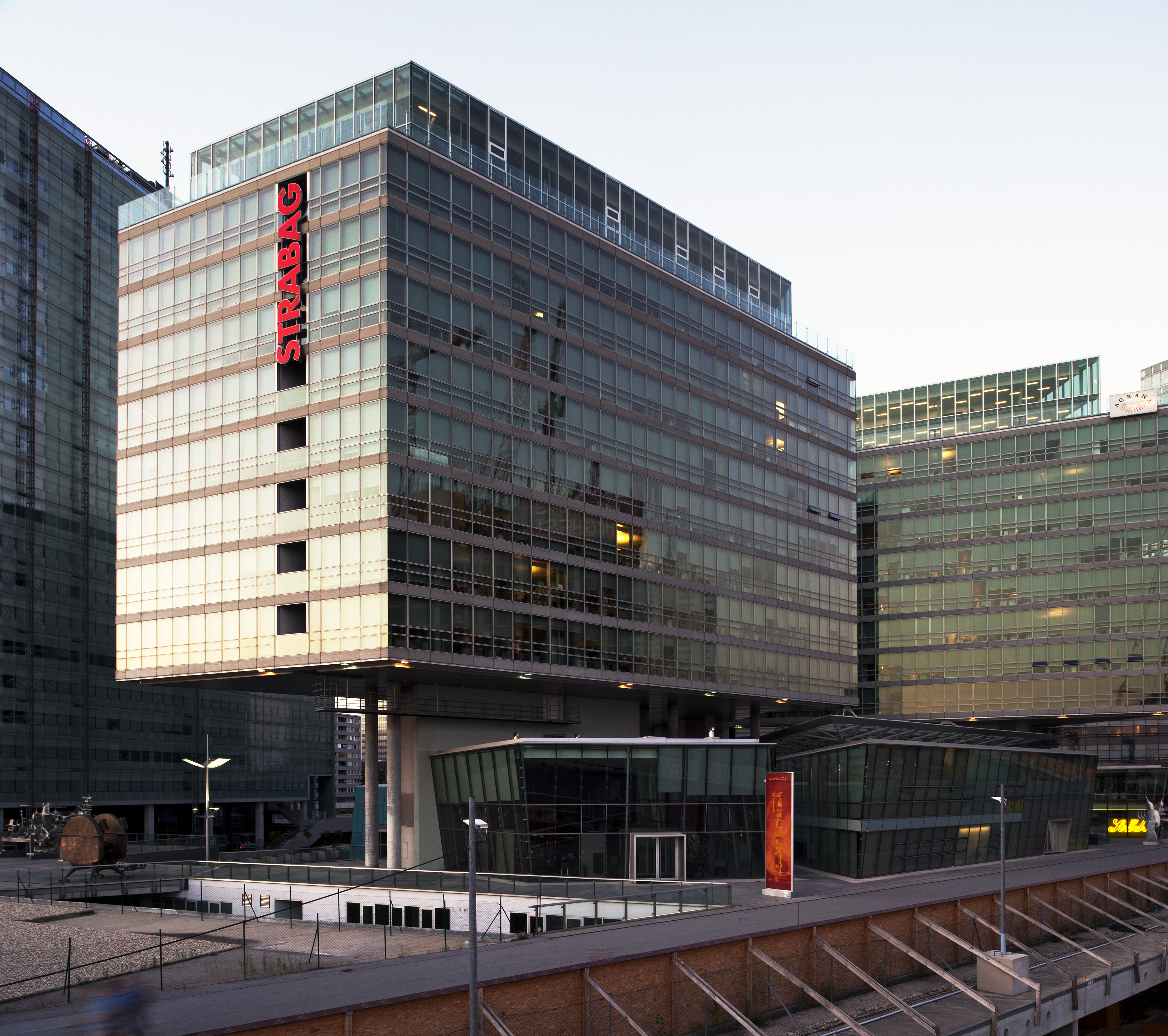 Zu sehen ist das beleuchtete STRABAG Haus bei Abenddämmerung in Wien. 