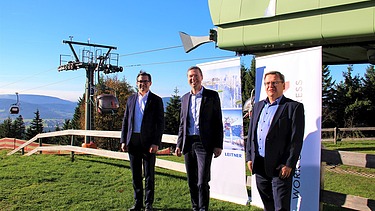 Foto von frei Männer in Anzug vor einer Seilbahn.  