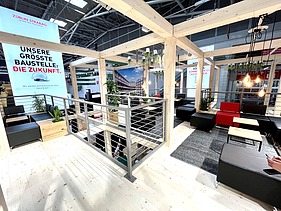 Foto von einem Messestand von STRABAG. Zu sehen ist eine Sitzecke.    