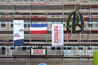 Foto von zwei Personen, die auf einem Gerüst stehen und den Richtspruch verkünden. 