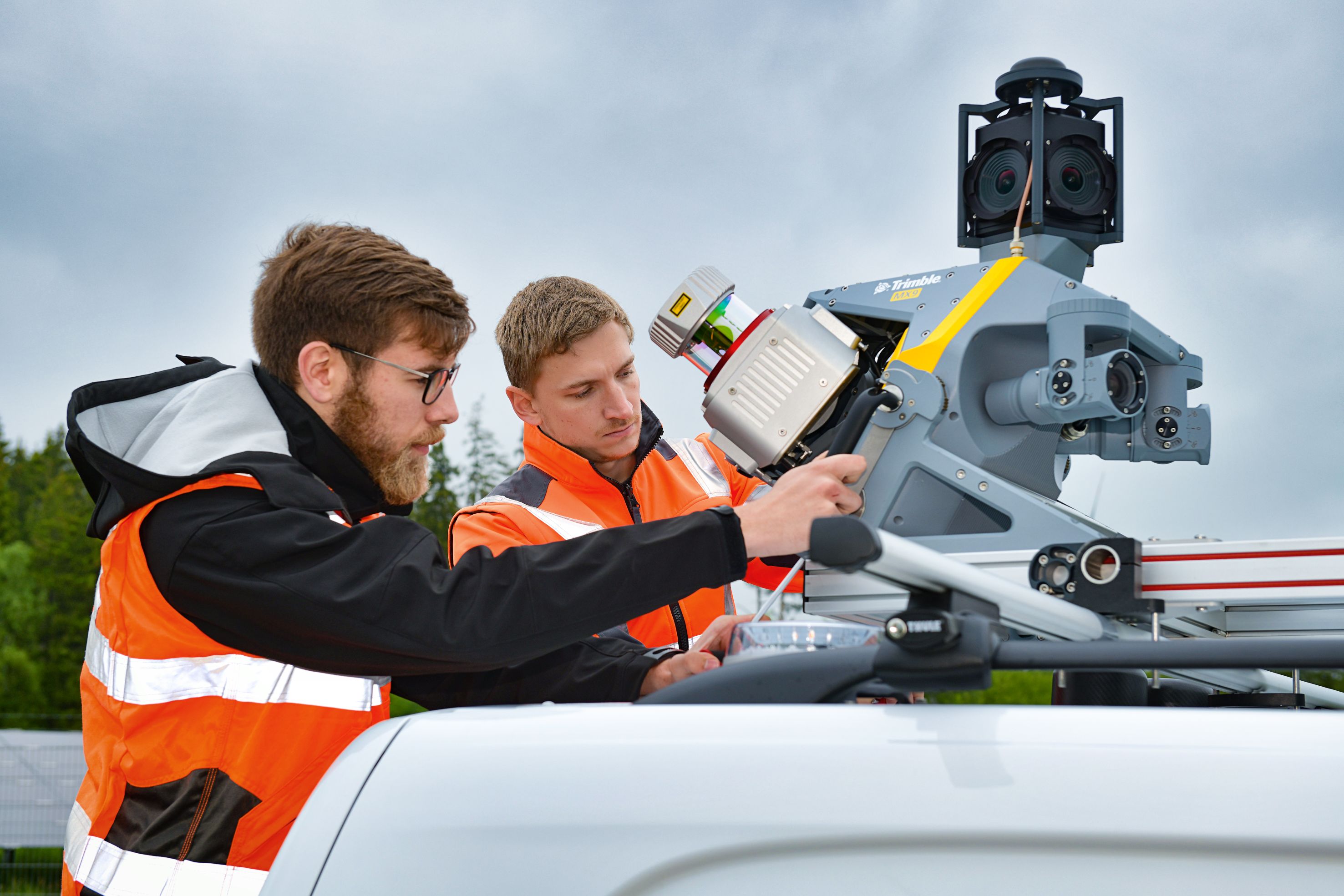 Foto von zwei Personen in Schutzwesten mit einem mobilen Laserscanner