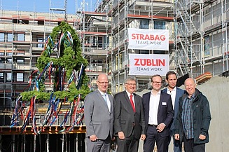 Foto von freundlich schauenden Männern auf einer Baustelle, beim hissen des Richtkranzes.  