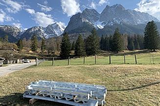 Foto von Stahlelementen die auf einer Wise vor einem Gebirge liegen.   