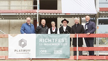 Foto von mehreren Personen auf einem Gerüst, beim Richtspruch. 