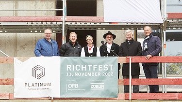 Foto von mehreren Personen auf einem Gerüst, beim Richtspruch. 