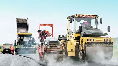 Foto zeigt drei Straßenbaumaschinen im Einsatz mit Fahrern