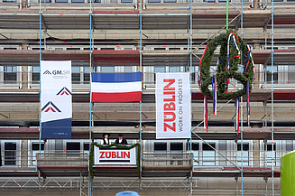 Foto von zwei Personen, die auf einem Gerüst stehen und den Richtspruch verkünden. 