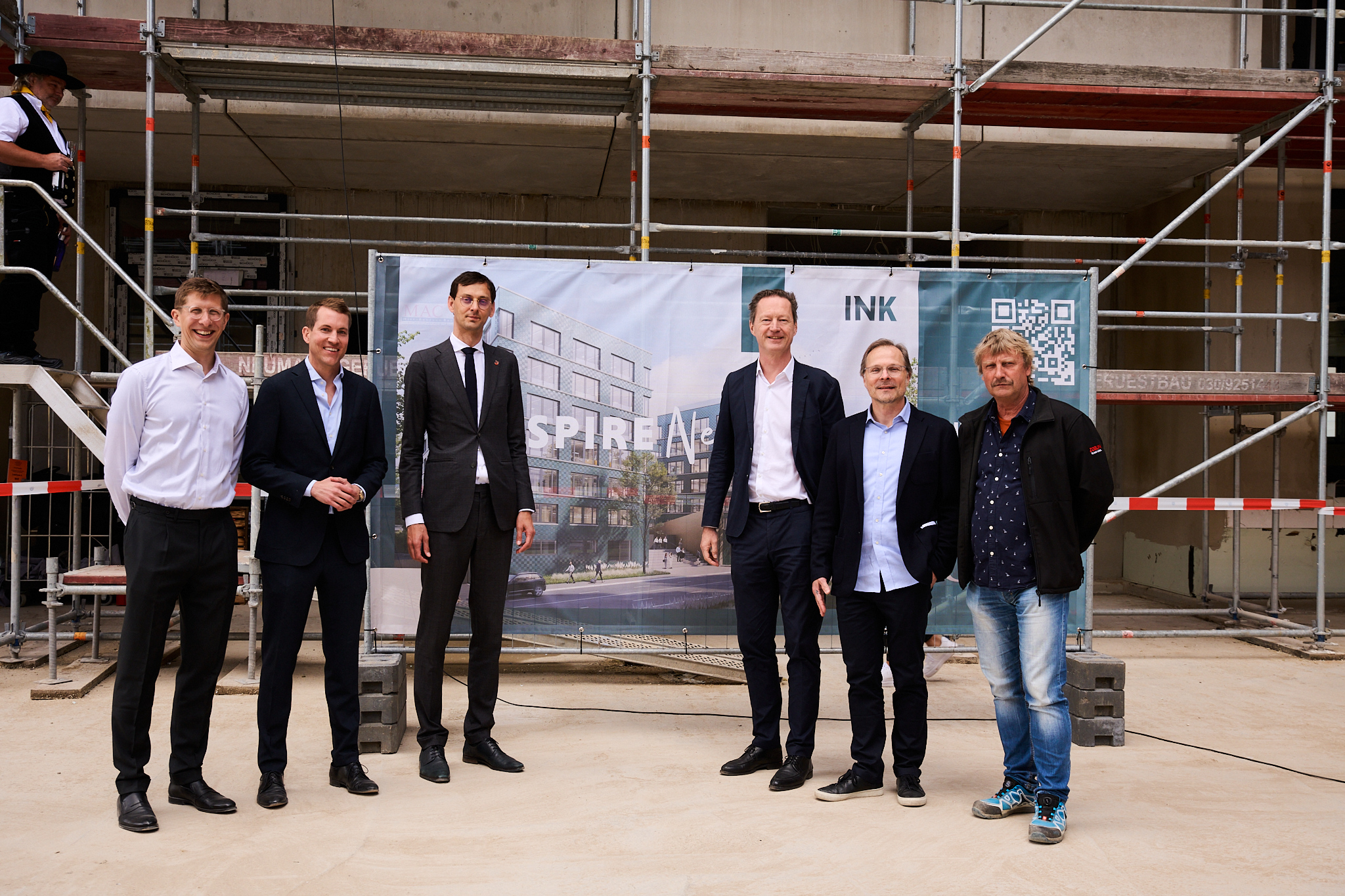 Foto von mehreren schick gekleideten Personen auf einer Baustelle.