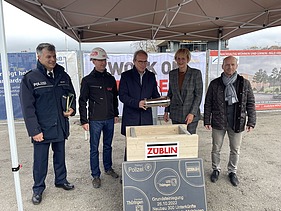 Foto mehreren Personen die eine Röhre in eine Holztruhe legen.   