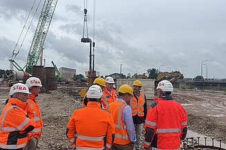 Mehrere Personen stehen in Sicherheitskleidung auf einer Baustelle