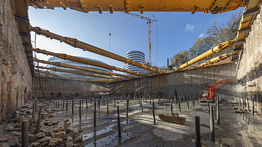 Foto von einem Loch auf einer Baustelle. Am Boden des Lochs sind Metallstäbe. 