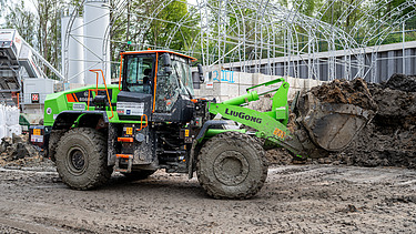 A large wheel loader transports soil in its bucket