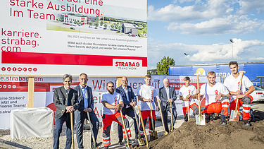 Das Foto zeigt mehrere Personen mit Schaufeln hinter einem Erdhaufen