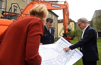 Foto drei Personen die sich Zeichnung anschauen. 