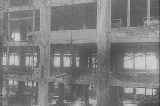  Schwarz-weiß Aufnahme von einem zerstörten mehrstöckigen Haus.